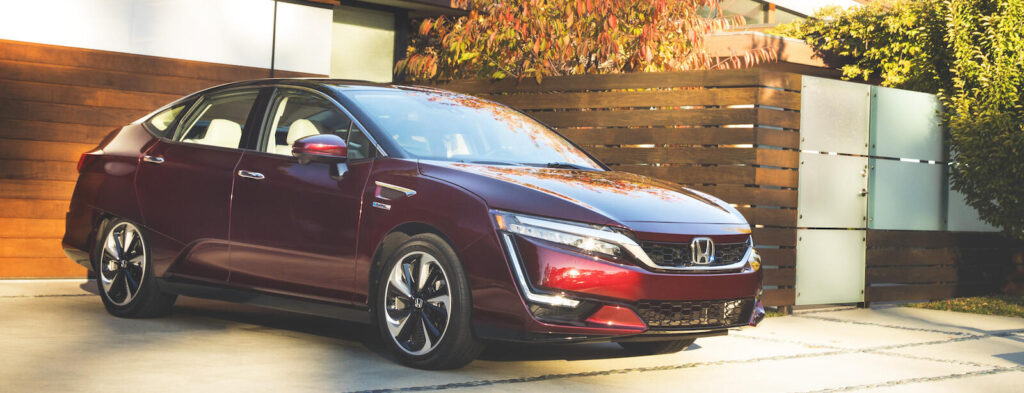 En röd Nissan EV parkerad framför ett modernt hus. (AI text)