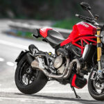En röd motorcykel kör nerför en väg. (AI text)