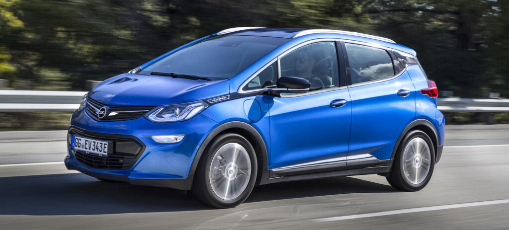 En blå Chevrolet Bolt EV kör längs en landsväg. (AI text)