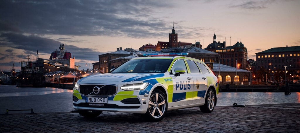 En polisbil parkerad framför ett byggnad. (AI text)