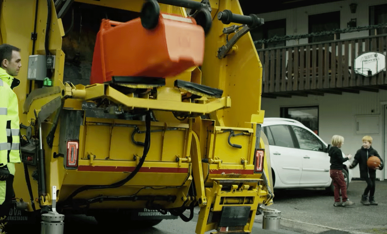 En man i gult väst står bredvid en gul sopbil. (AI text)