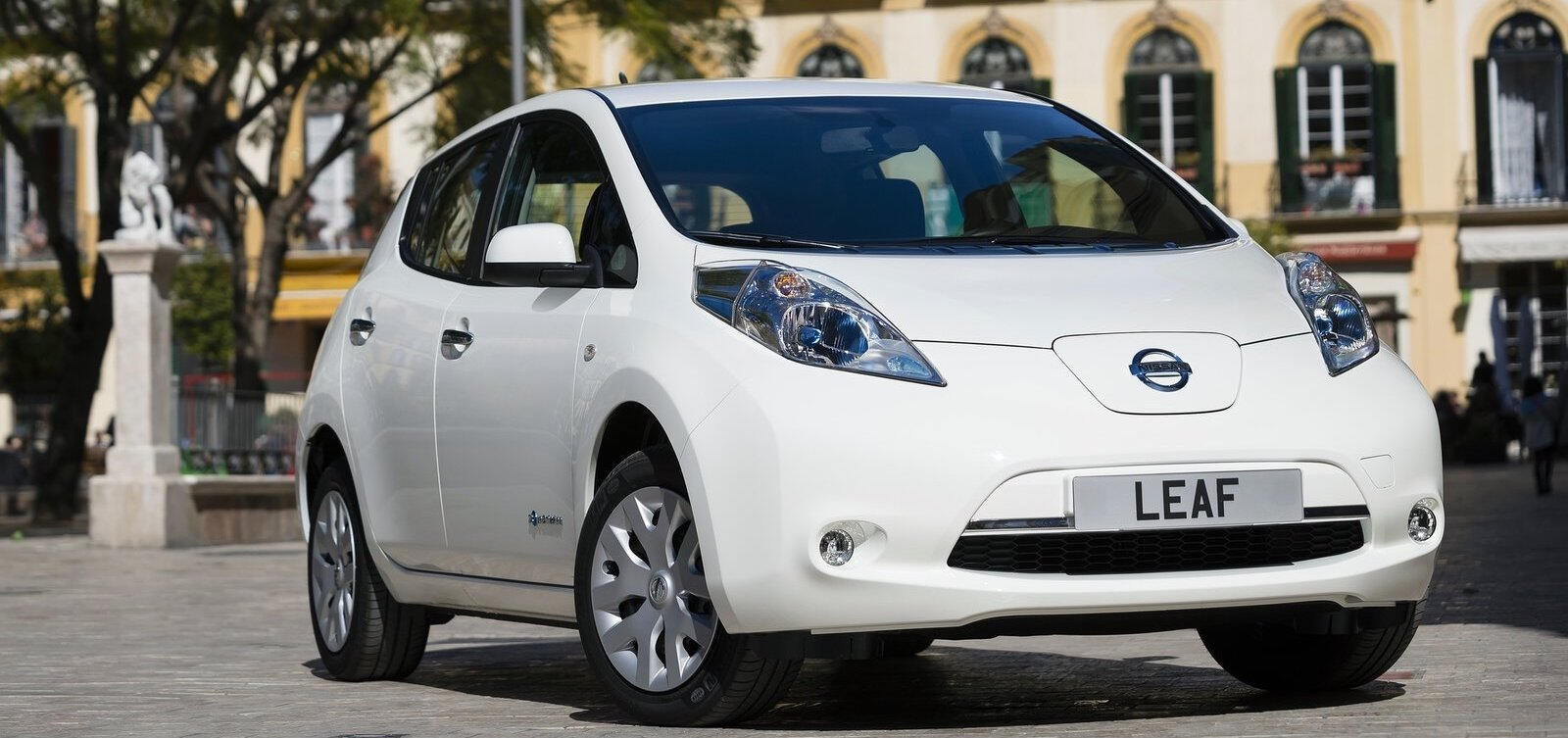 En vit Nissan Leaf parkerad i en stad. (AI text)