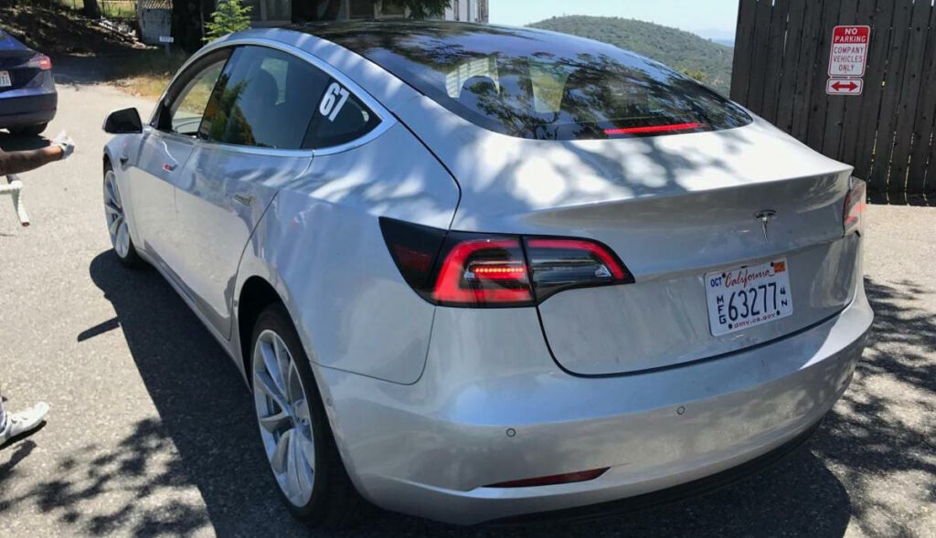 En Tesla Model 3 parkerad på en parkeringsplats. (AI text)