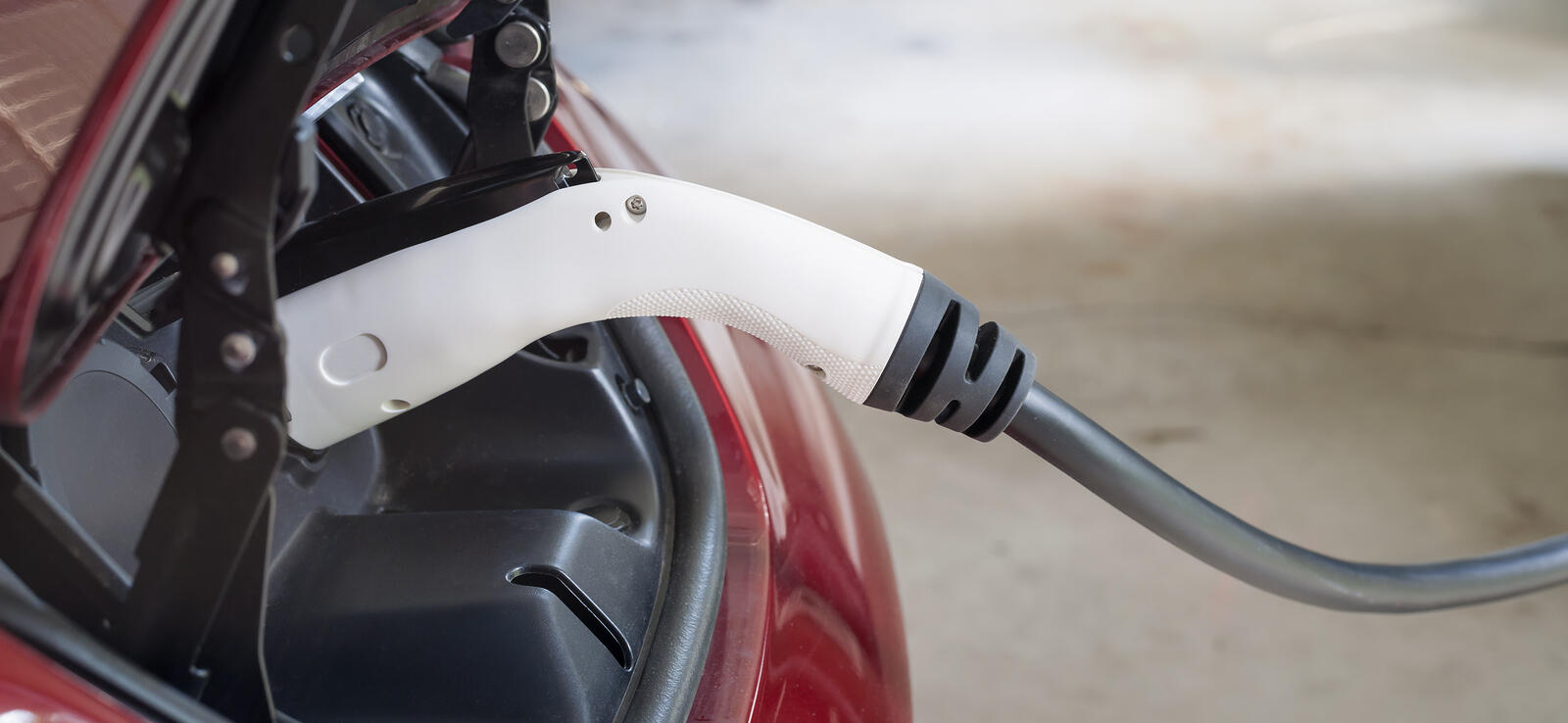 En röd bil är uppkopplad från en el-laddare. (AI text)