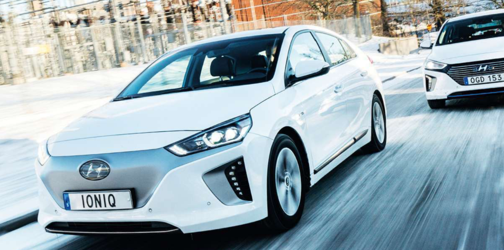 Två vita bilar kör nerför en snöig gata. (AI text)