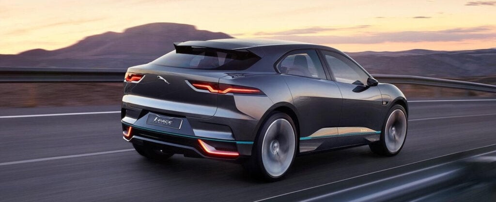 En Jaguar I Pace kör nerför en bergsväg. (AI text)