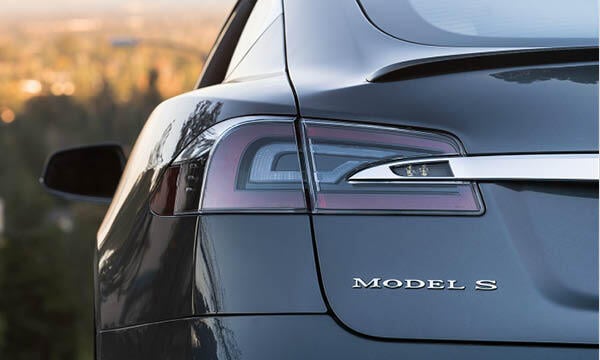 En Tesla Model S parkerad på en backe. (AI text)