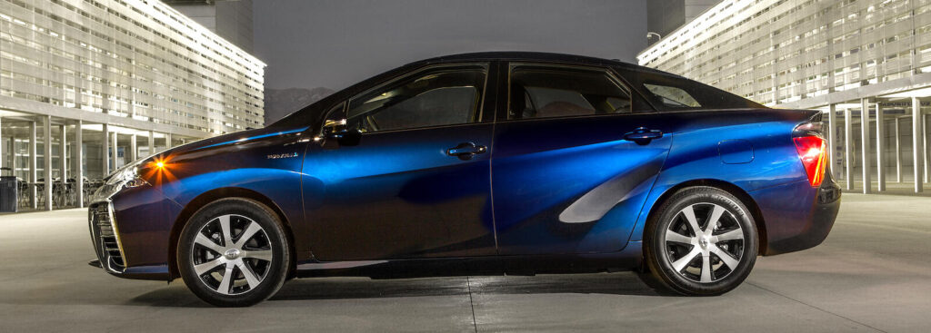 En blå Toyota Prius parkerad framför ett byggnad. (AI text)