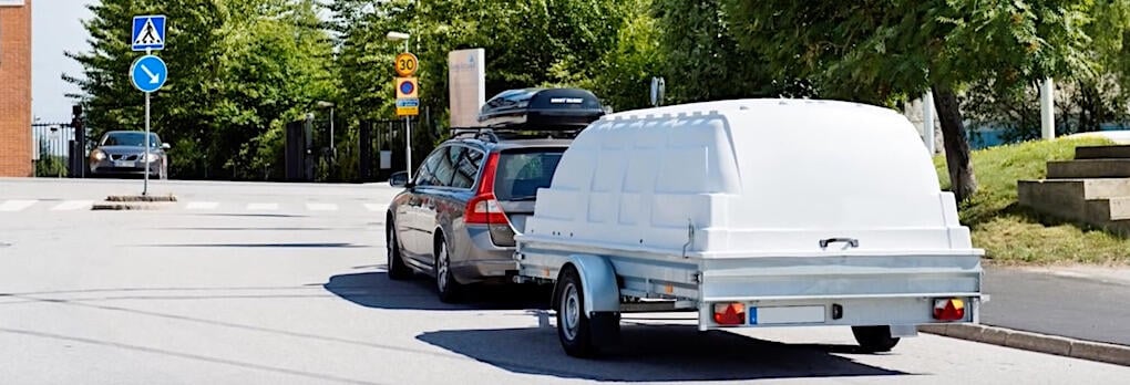 En bil med en släp på vägen. (AI text)