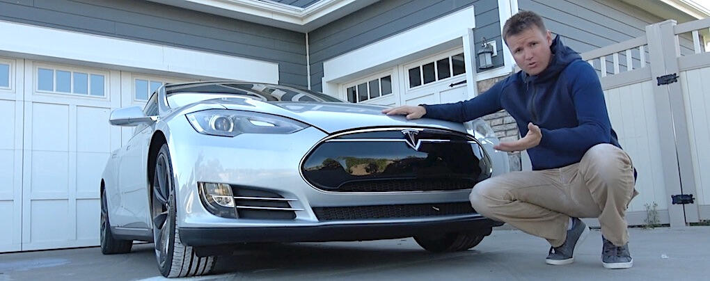 En man knorrar framför en Tesla Model S. (AI text)