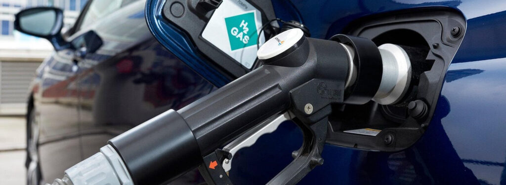 En blå bil står parkerad vid en bensinstation. (AI text)