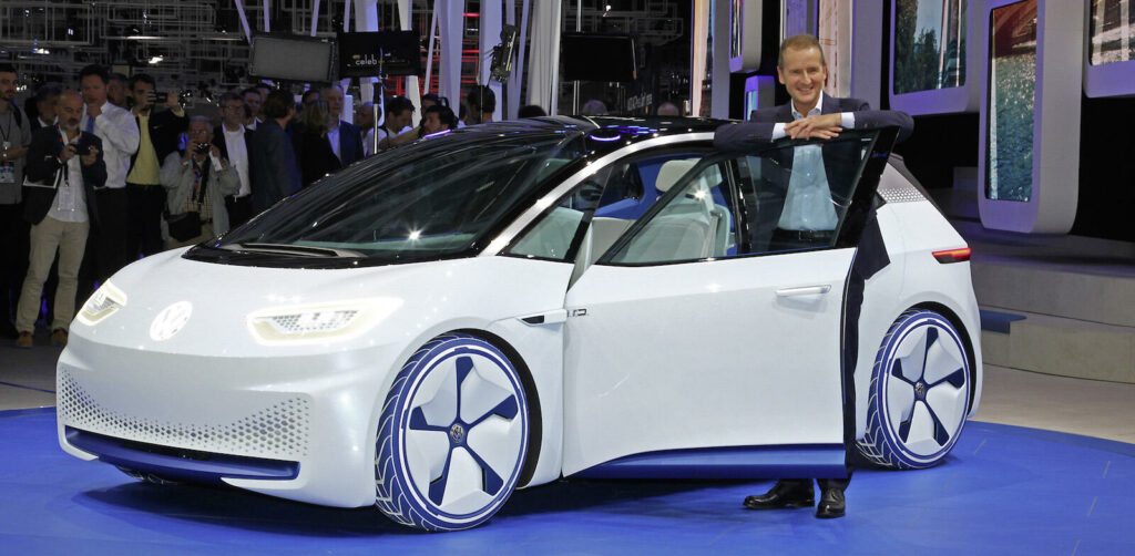 En man står bredvid en Volkswagen ID-bil på bilsalongen. (AI text)