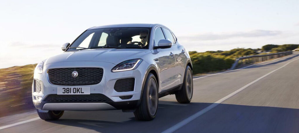 En vit jaguar F-Pace kör ner en landsväg. (AI text)