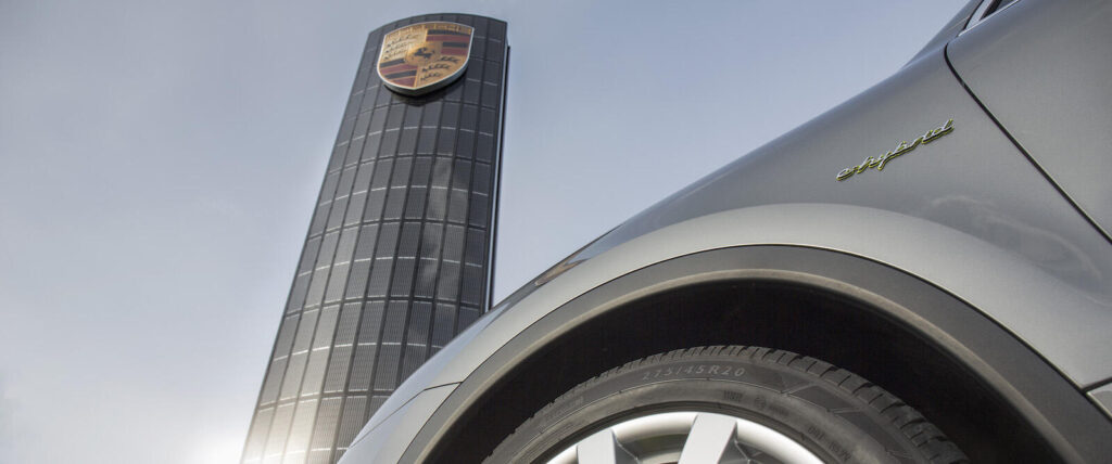 En Porsche Cayenne parkerad framför en tornbyggnad. (AI text)