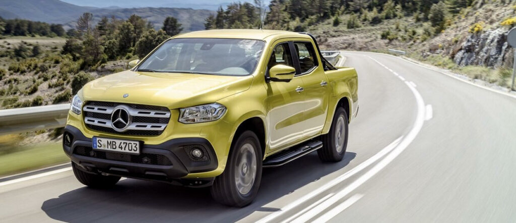 En gul Mercedes-Benz lastbil kör nerför en bergsväg. (AI text)