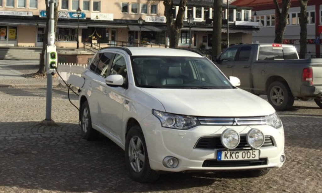 En vit SUV parkerad på en gata. (AI text)