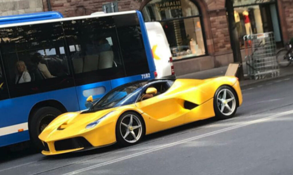 En gul Ferrari F12tdf parkerad framför en buss. (AI text)