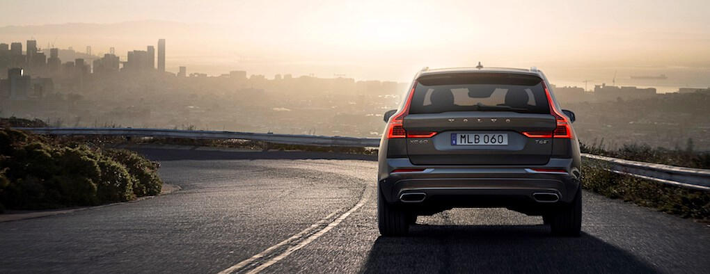 En SUV kör nedför en väg med en stad i bakgrunden. (AI text)