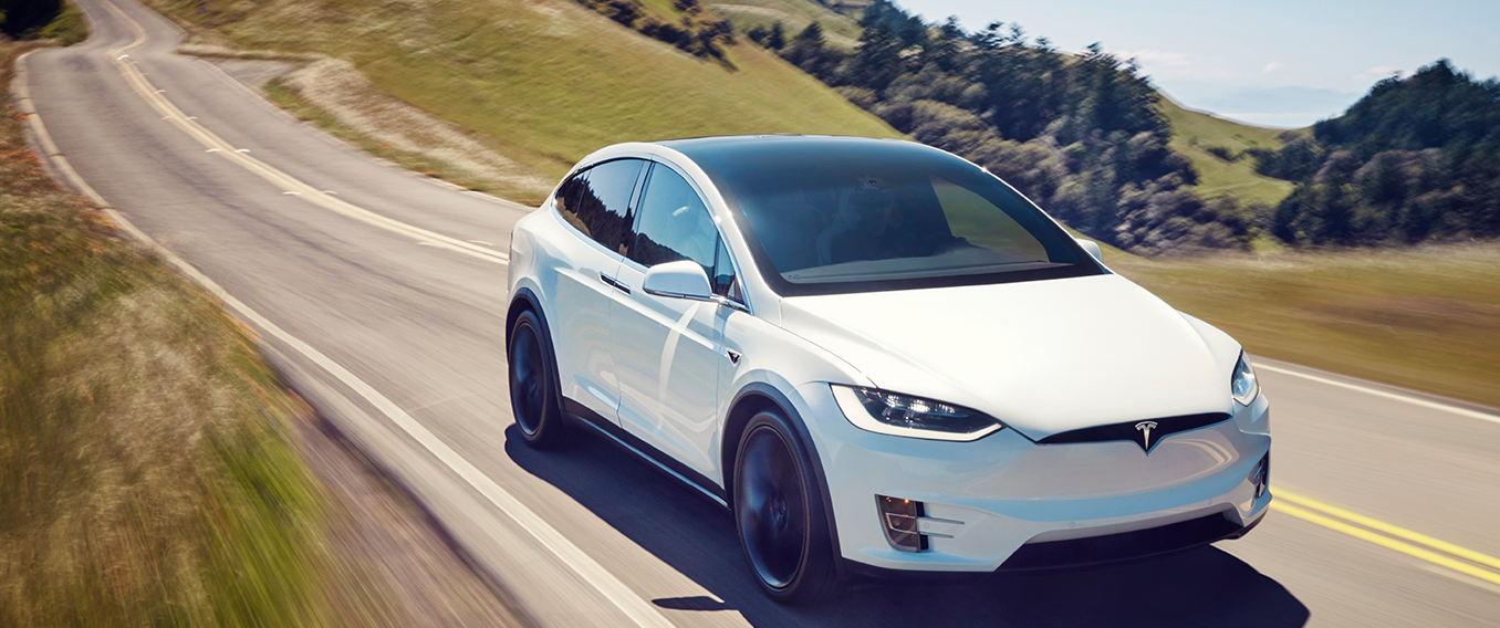 En Tesla Model X kör nedför en bergväg. (AI text)