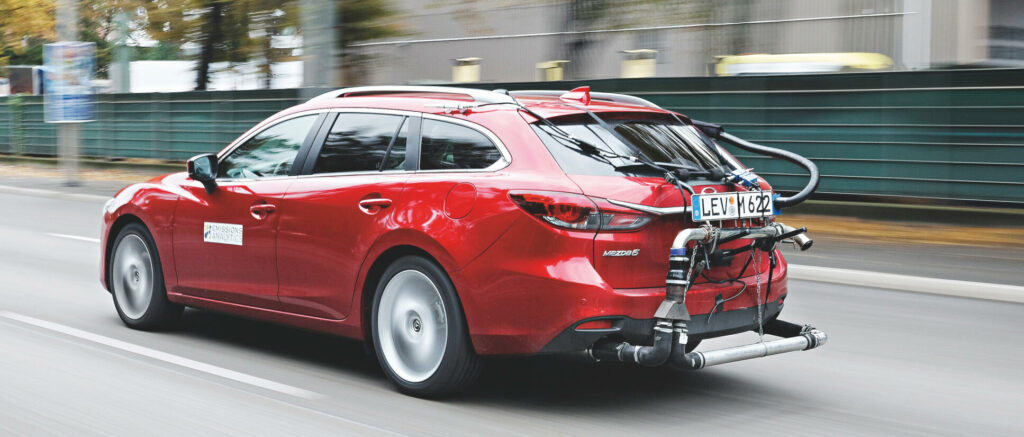 En röd bil kör nedför en stadsgata. (AI text)