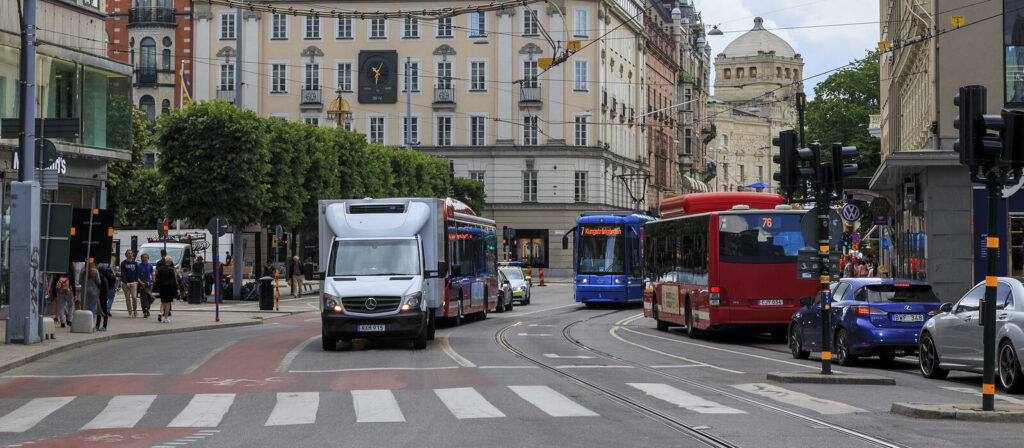 En stadsgata med bilar och bussar. (AI text)