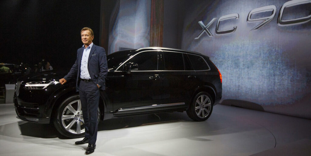 En man står bredvid en Volvo XC90 SUV på Shanghais bilsalong. (AI text)