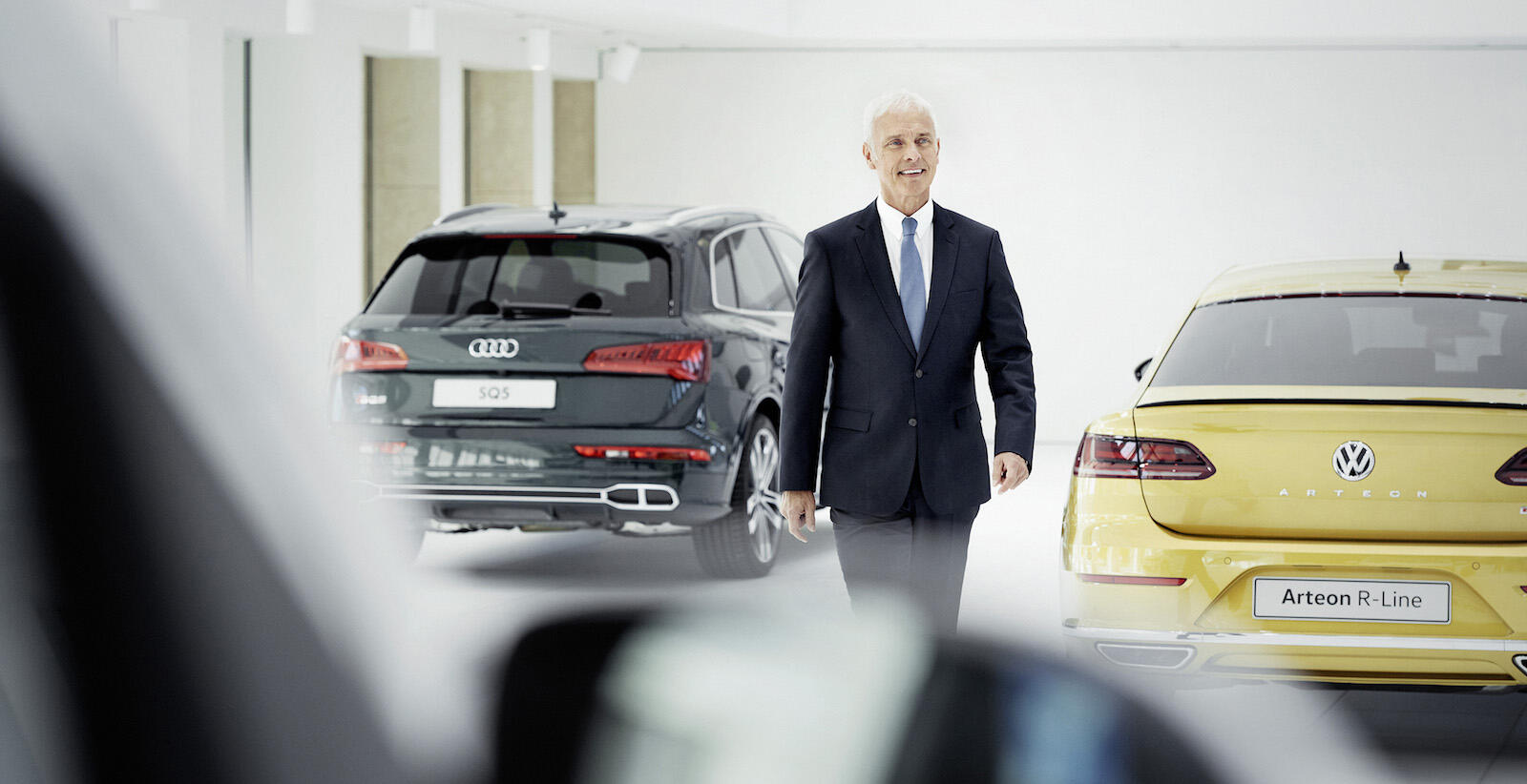 En man i kostym går förbi en rad bilar. (AI text)