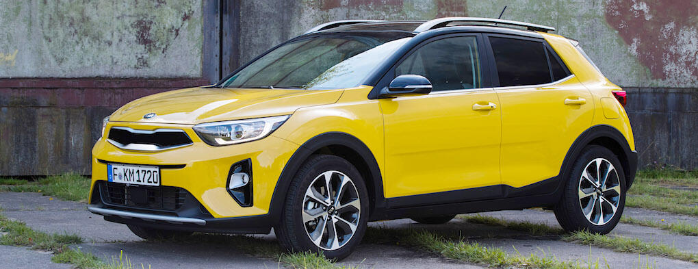 En gul Kia Rio står parkerad framför ett gammalt byggnad. (AI text)