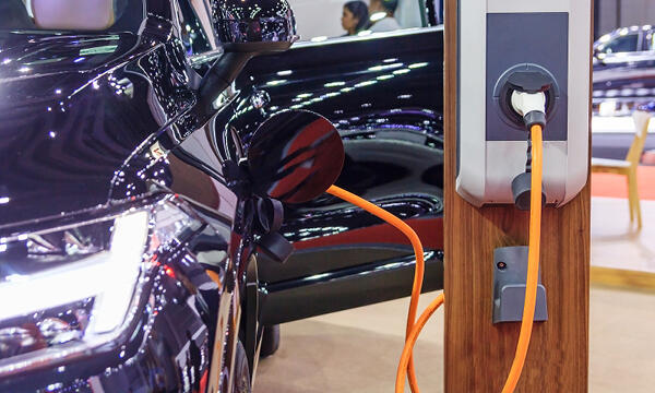 En bil är uppkopplad till en elbilsladdare på en bilsalong. (AI text)