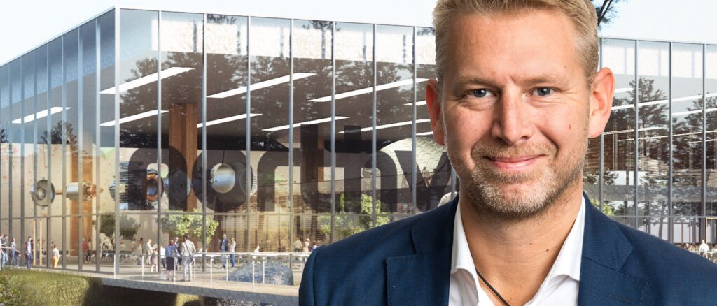 En man i kostym står framför ett byggnad. (AI text)