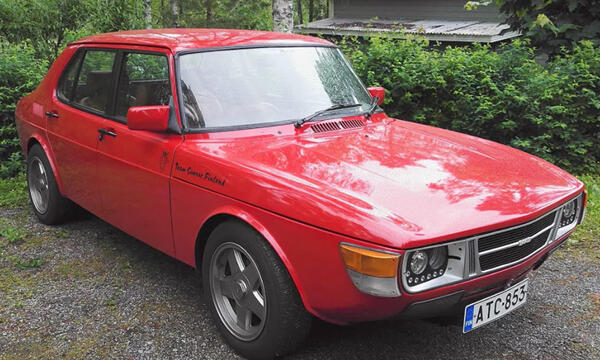 En röd bil parkerad i en infartsväg. (AI text)