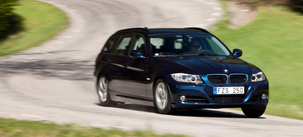 BMW X1 Touring kör nedför en krökt väg. (AI text)