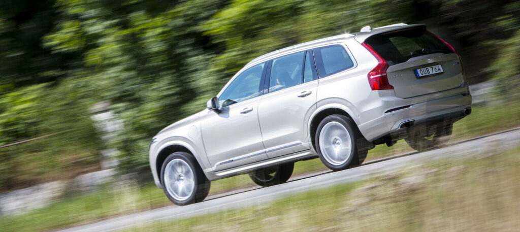 En Volvo XC90 SUV kör längs en landsväg. (AI text)