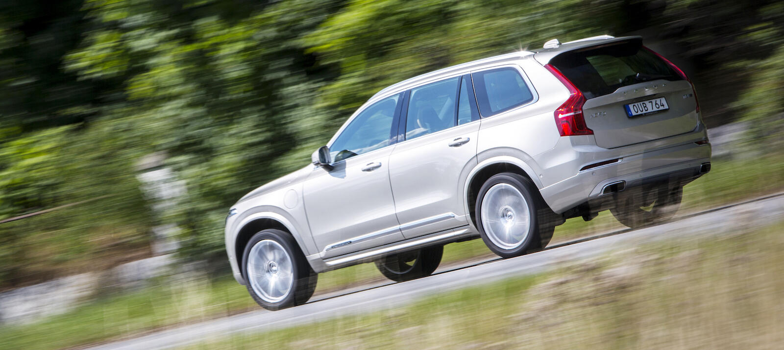 En Volvo XC90 SUV kör längs en landsväg. (AI text)