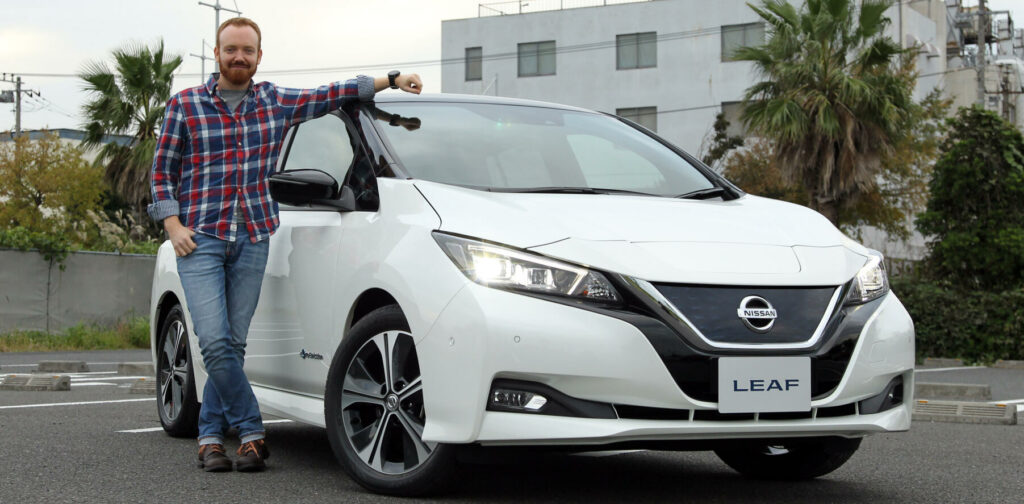 En man står bredvid en Nissan Leaf. (AI text)