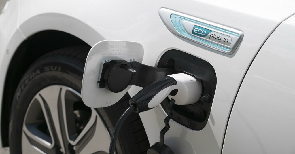 En vit bil är uppkopplad till en elladdare. (AI text)