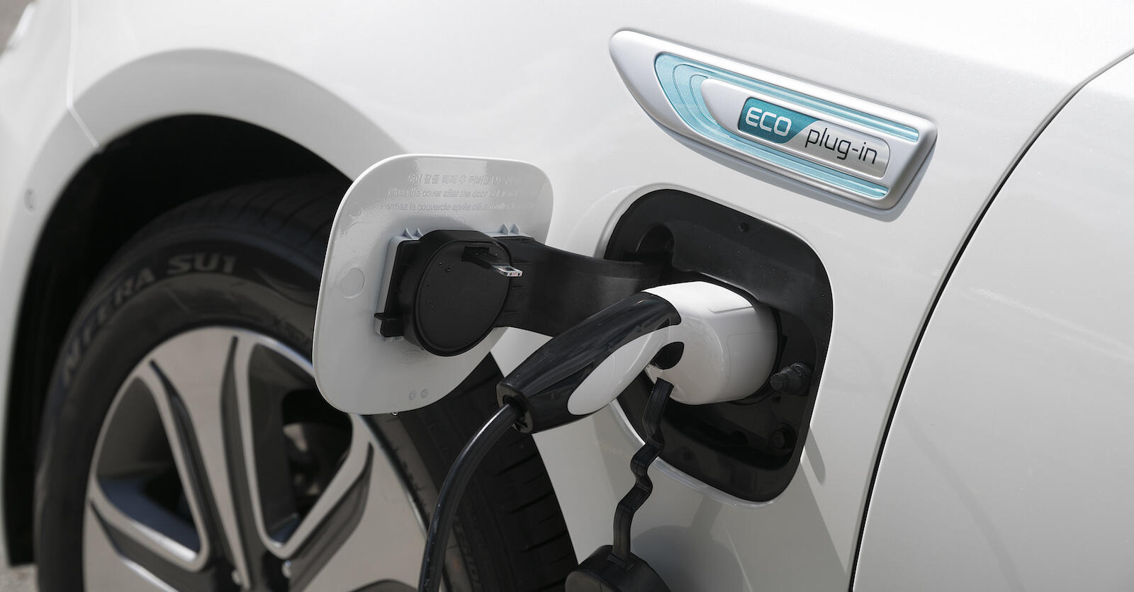 En vit bil är uppkopplad till en elladdare. (AI text)