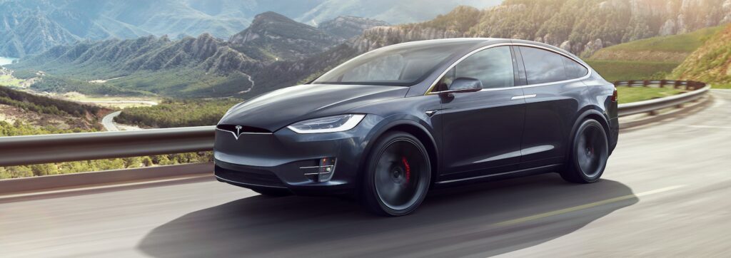 Tesla Model X kör på en bergsväg. (AI text)