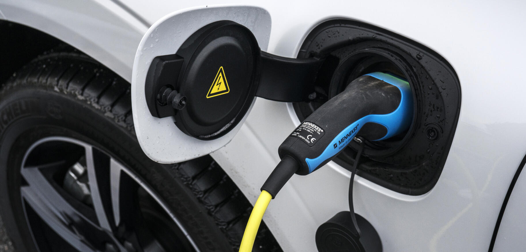 En vit bil är uppkopplad till en el-laddare. (AI text)
