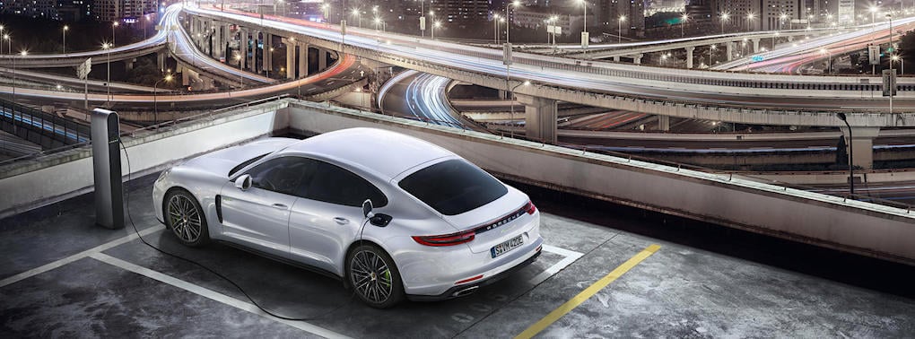 En vit bil parkerad i en parkeringsplats på natten. (AI text)