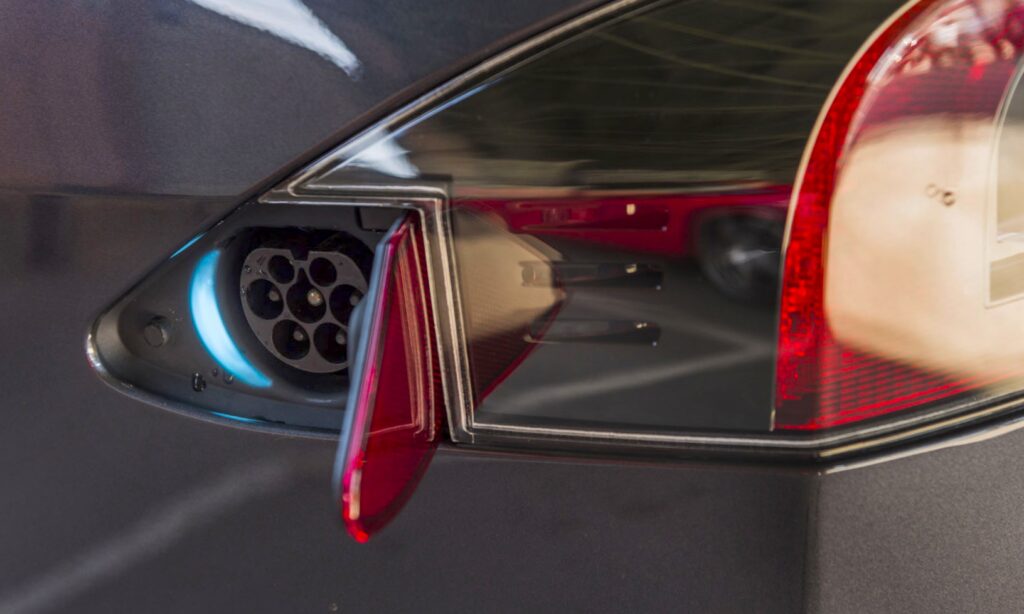 En bil laddar på en elbilscharger. (AI text)