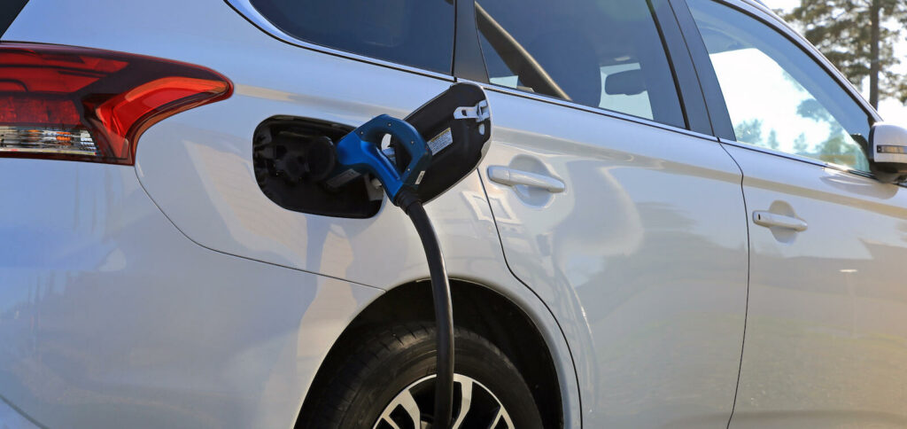 En vit bil är uppkopplad till en laddare. (AI text)