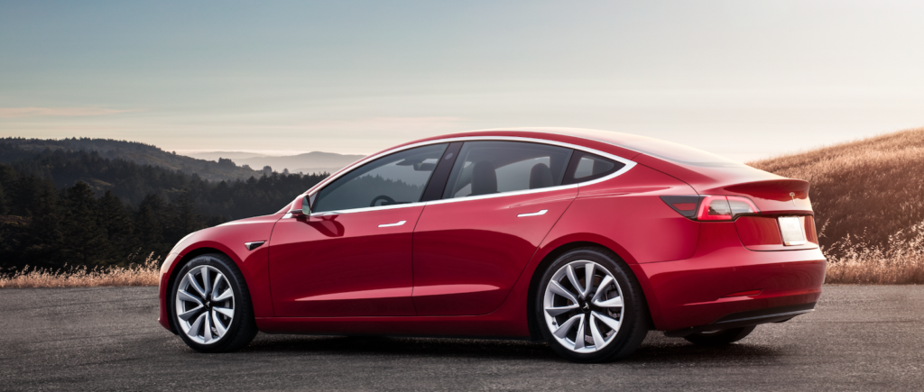 En röd Tesla Model 3 parkerad vid vägkanten. (AI text)
