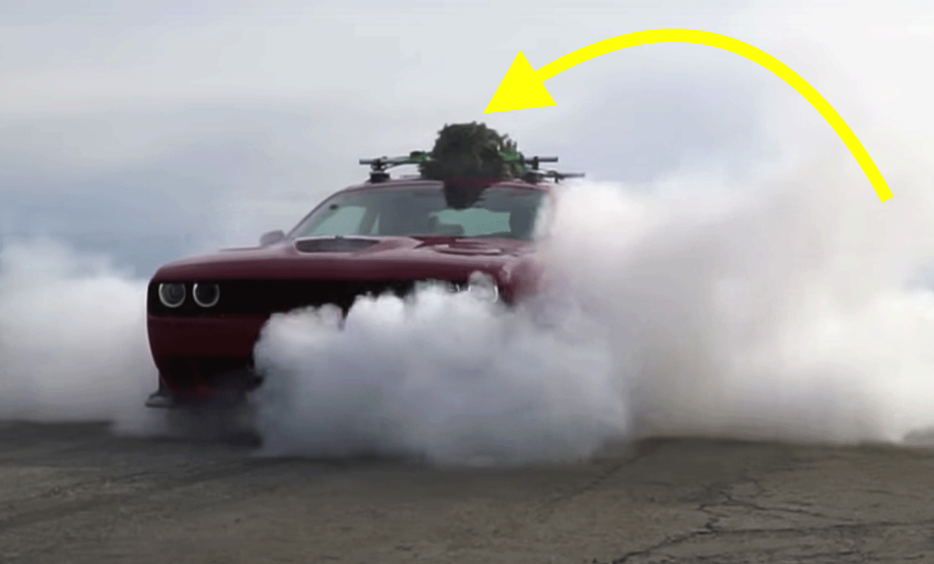 En röd Dodge Challenger kör nerför vägen med rök som kommer ut. (AI text)