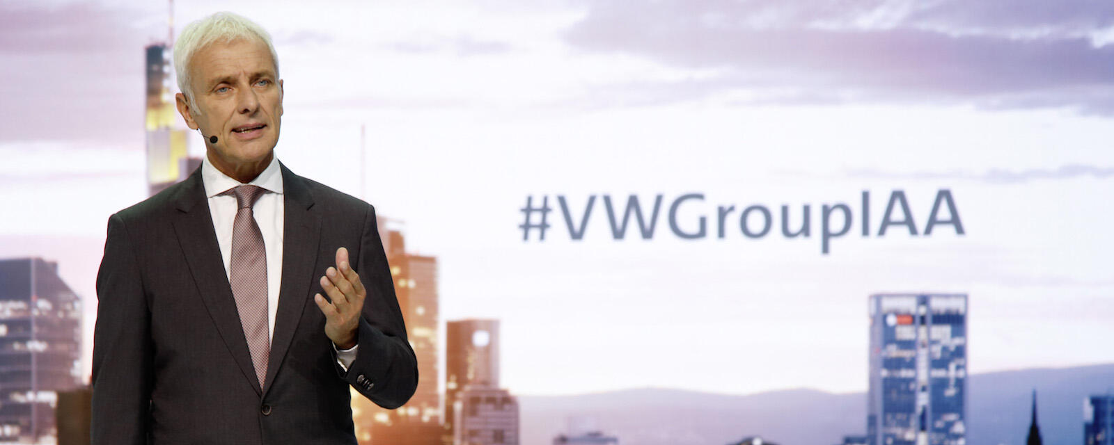 En man i kostym står framför ett byggnad. (AI text)