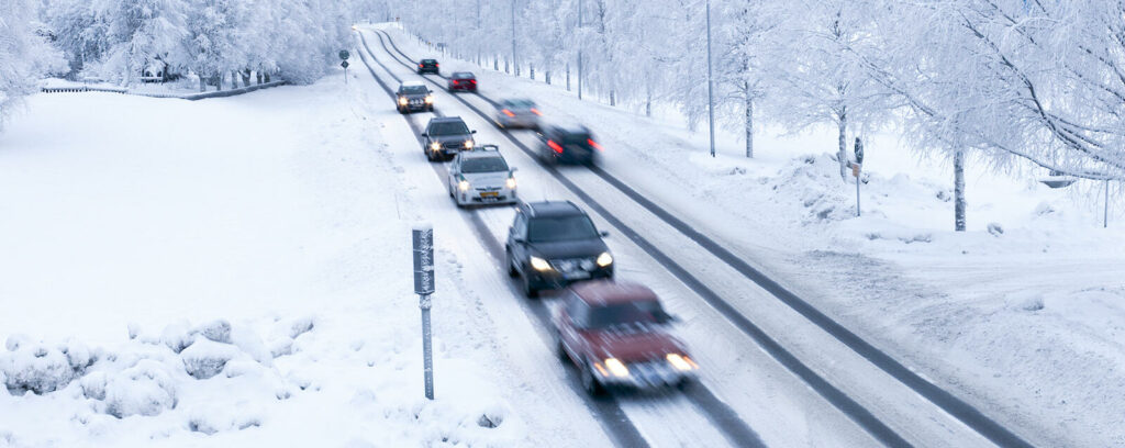 En grupp bilar kör nedför en snöig väg. (AI text)
