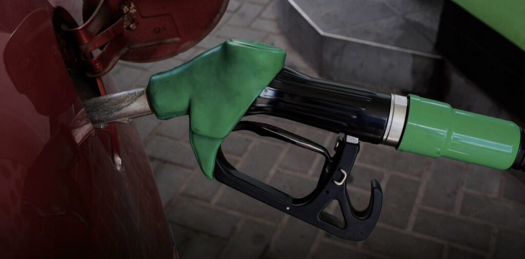 En grön bil tankar med bränsle vid en bensinstation i en stad. (AI text)