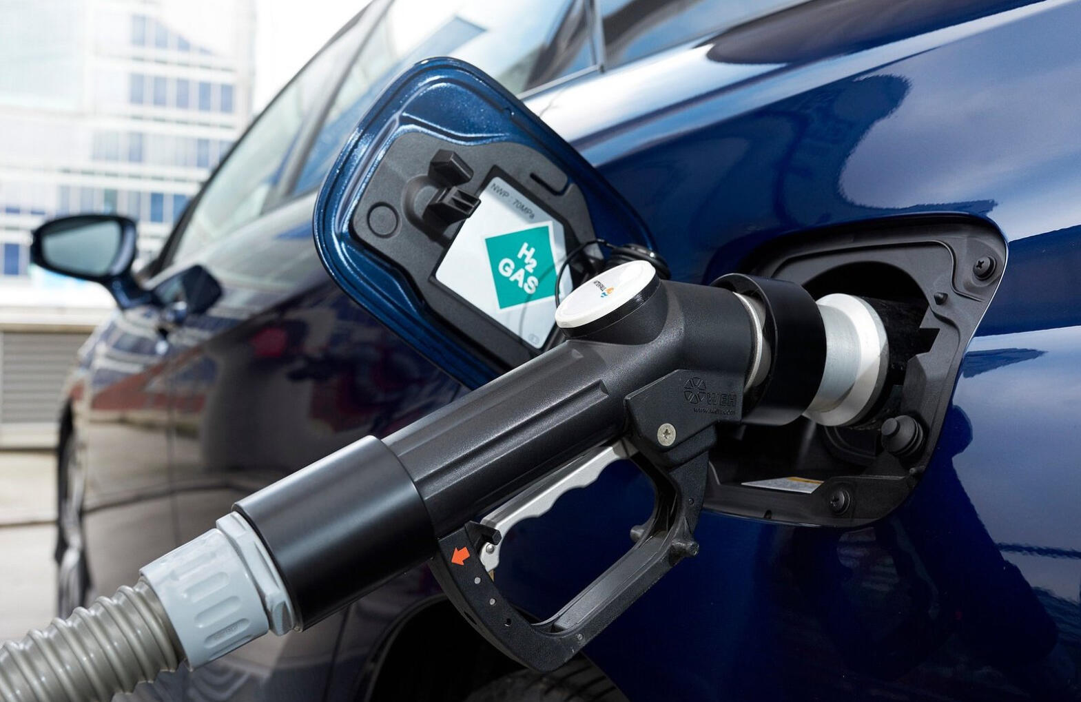 En blå bil står parkerad vid en bensinstation. (AI text)