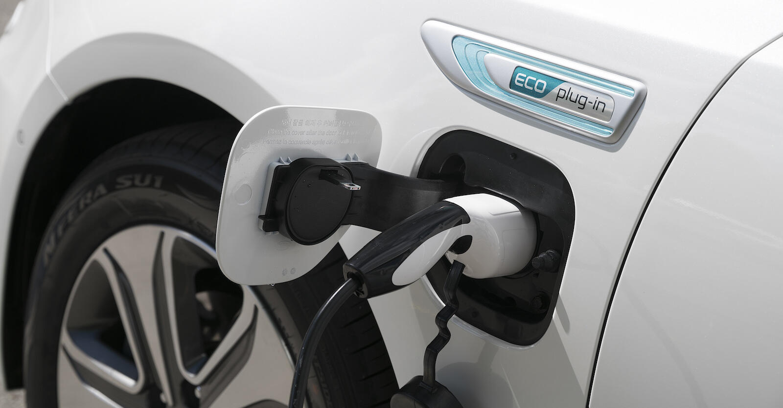 En vit bil är uppkopplad till en elladdare. (AI text)