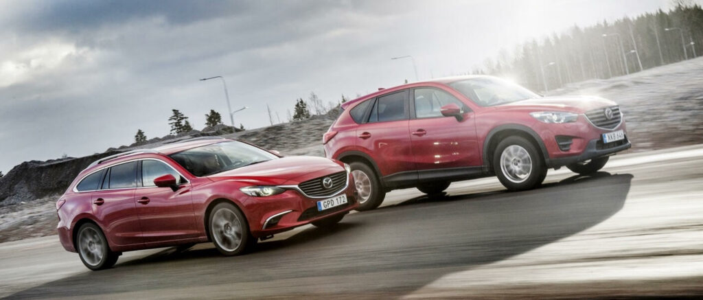 Två röda Mazda CX-5 SUV:er kör på en väg. (AI text)